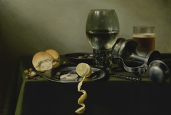 Still life with roemer, an overturned pewter jug, olives, and half-peeled lemon on pewter plates by Pieter Claesz