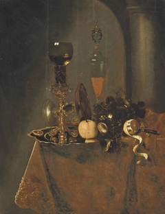 A roemer filled with wine and a lemon on a silver charger, an upturned tazza, a wine flute with a lid, grapes, a partly-peeled lemon and a knife on a draped table in an interior by Gerard van Berleborch